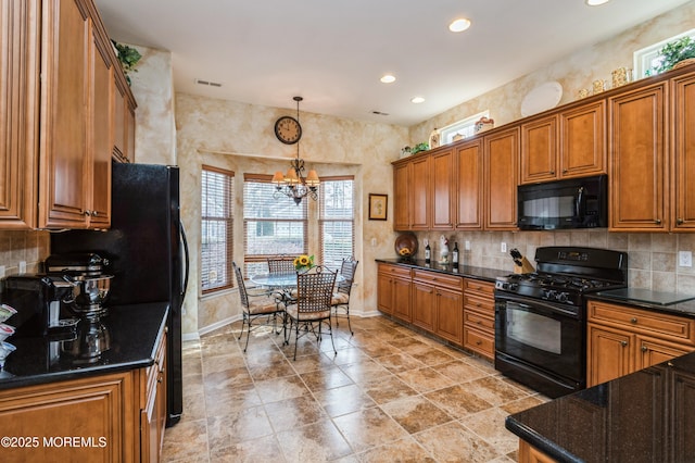 kitchen with decorative light fixtures, backsplash, dark stone countertops, black appliances, and an inviting chandelier