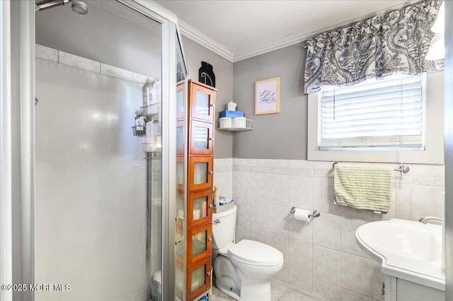 bathroom featuring vanity, toilet, ornamental molding, tile walls, and a shower with shower door