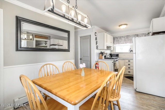 dining space with crown molding and light hardwood / wood-style flooring