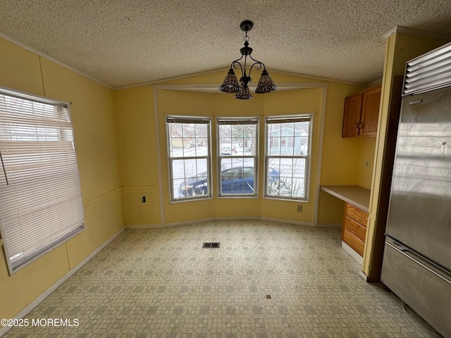 unfurnished dining area with a chandelier, a textured ceiling, vaulted ceiling, and a healthy amount of sunlight