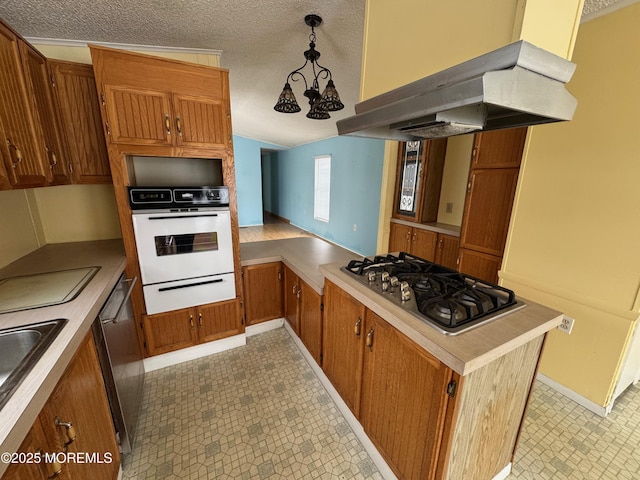 kitchen with hanging light fixtures, a textured ceiling, appliances with stainless steel finishes, kitchen peninsula, and island exhaust hood