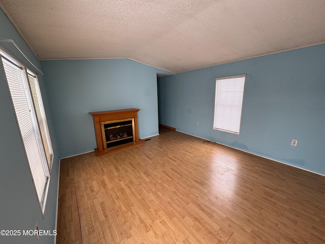 unfurnished living room with a textured ceiling, light hardwood / wood-style flooring, and vaulted ceiling