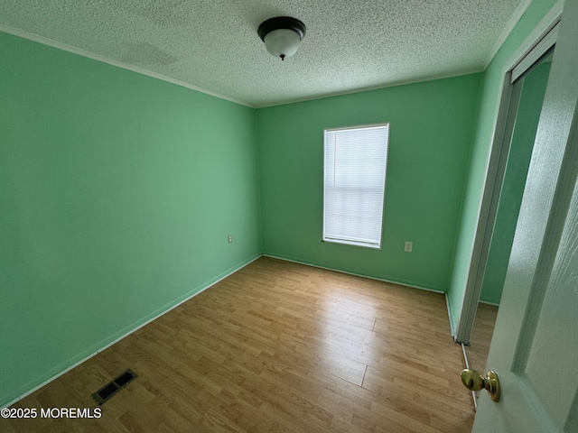 unfurnished room with a textured ceiling and light hardwood / wood-style flooring