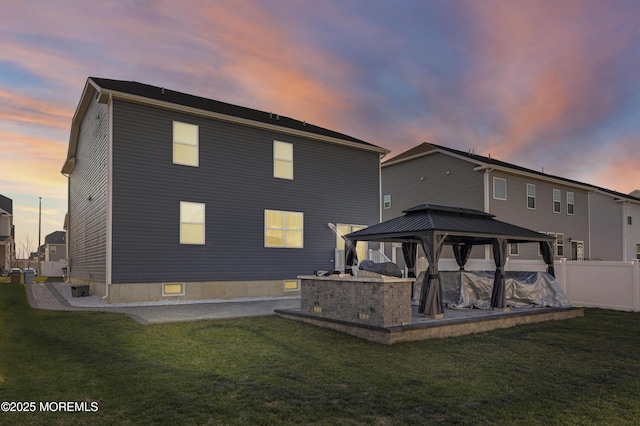 back house at dusk with a gazebo, central air condition unit, and a yard