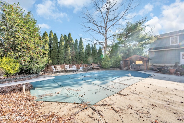 view of pool with a diving board and a patio