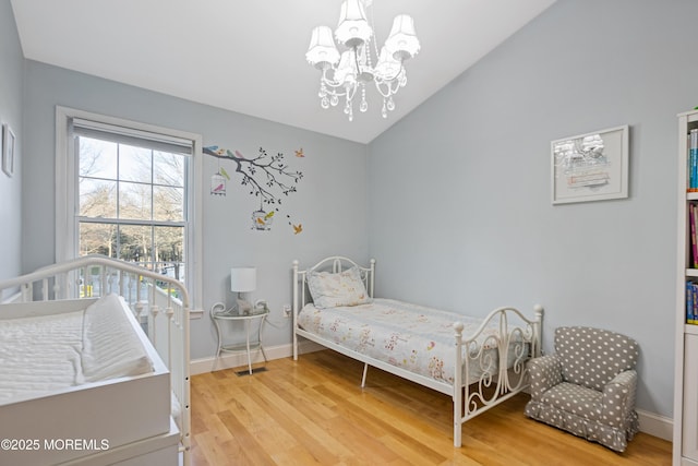 bedroom featuring an inviting chandelier, hardwood / wood-style floors, and vaulted ceiling