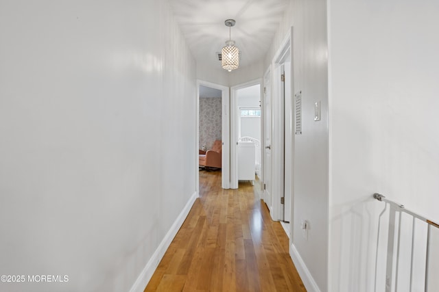 corridor featuring a notable chandelier and light wood-type flooring