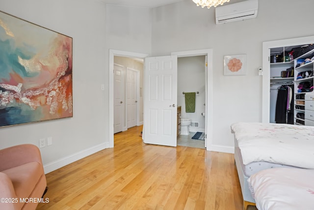 bedroom with ensuite bath, a closet, hardwood / wood-style floors, and a wall mounted air conditioner