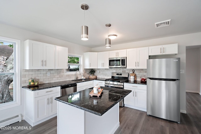 kitchen with decorative light fixtures, stainless steel appliances, a baseboard radiator, and white cabinetry