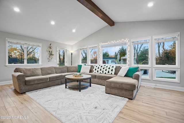 living room featuring a wealth of natural light, lofted ceiling with beams, and light hardwood / wood-style floors