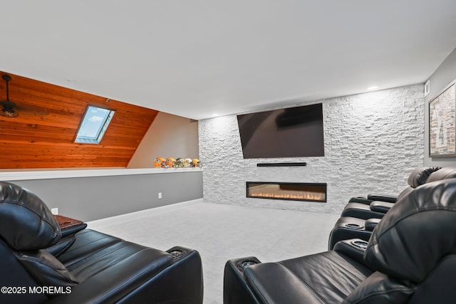 carpeted home theater with a fireplace and a skylight