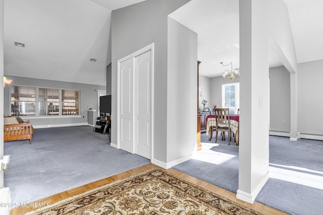 foyer featuring wood-type flooring, an inviting chandelier, baseboard heating, and lofted ceiling