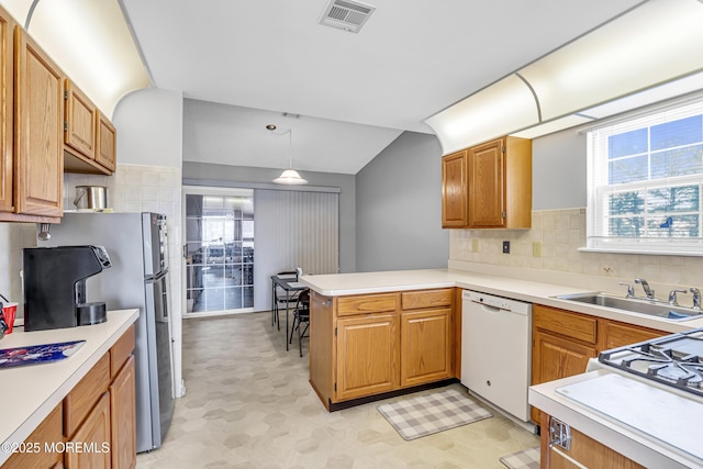 kitchen featuring pendant lighting, white dishwasher, sink, kitchen peninsula, and stainless steel refrigerator