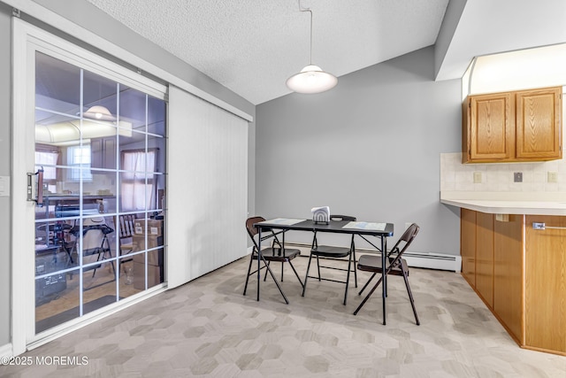 dining space featuring vaulted ceiling, a baseboard radiator, and a textured ceiling