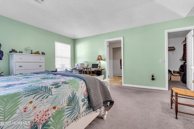 carpeted bedroom with a textured ceiling, a walk in closet, a baseboard radiator, and a closet