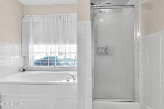 bathroom with shower with separate bathtub and tile walls