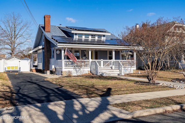 view of front of home with solar panels, a porch, and a front yard