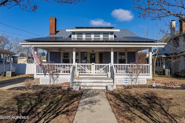 bungalow-style home with solar panels, covered porch, and central air condition unit