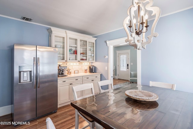 dining area featuring wood-type flooring, crown molding, and a notable chandelier