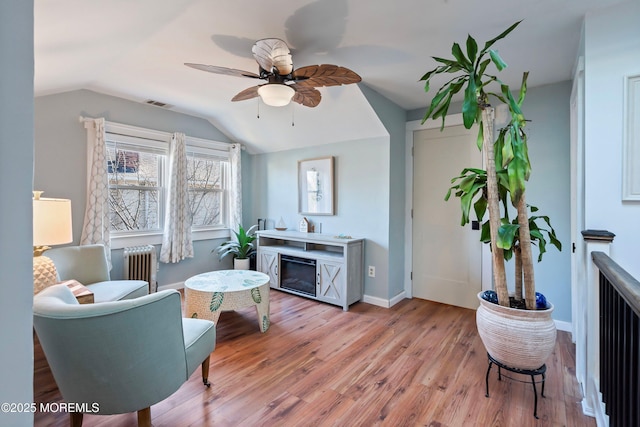 sitting room featuring light hardwood / wood-style flooring, vaulted ceiling, radiator, and ceiling fan