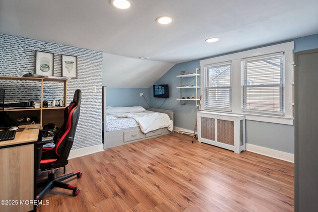 bedroom featuring radiator, light hardwood / wood-style flooring, and lofted ceiling