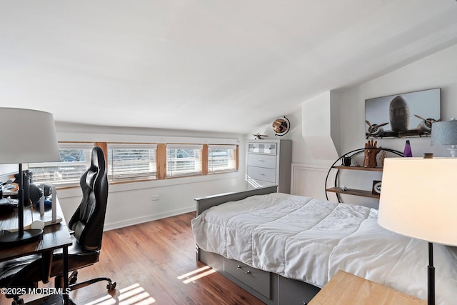 bedroom with light wood-type flooring, lofted ceiling, and multiple windows