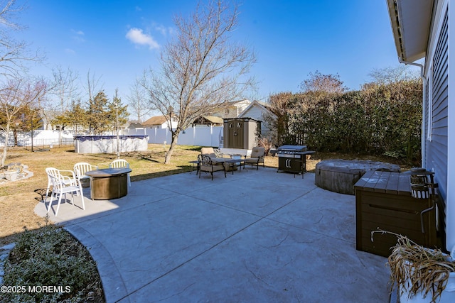 view of patio featuring a fire pit, a swimming pool with hot tub, a storage shed, and grilling area