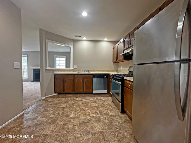 kitchen with sink, stainless steel appliances, and light carpet