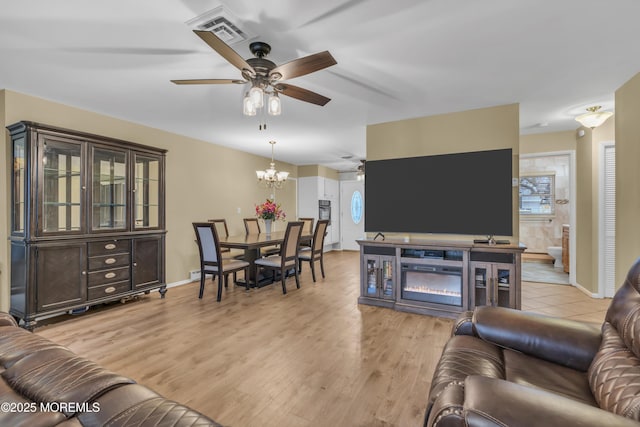 living room with ceiling fan with notable chandelier and light wood-type flooring