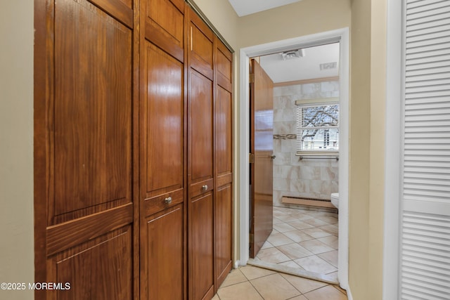 hallway featuring light tile patterned floors, tile walls, and baseboard heating