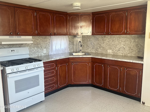 kitchen featuring white range with gas stovetop, backsplash, and sink