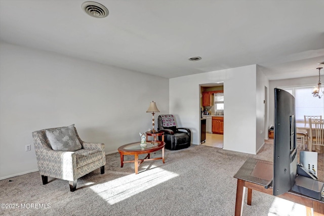 living area featuring light colored carpet and an inviting chandelier