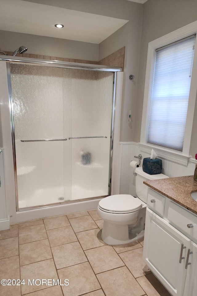 bathroom with vanity, toilet, a shower with door, and tile patterned flooring