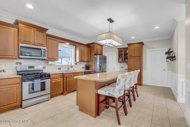 kitchen with a kitchen island, ornamental molding, appliances with stainless steel finishes, and pendant lighting