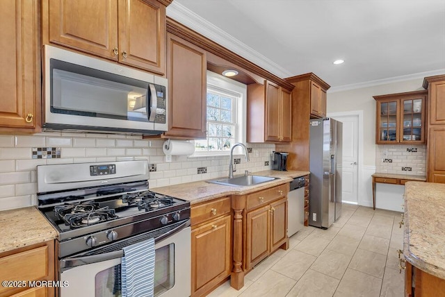 kitchen featuring stainless steel appliances, crown molding, light stone countertops, and sink