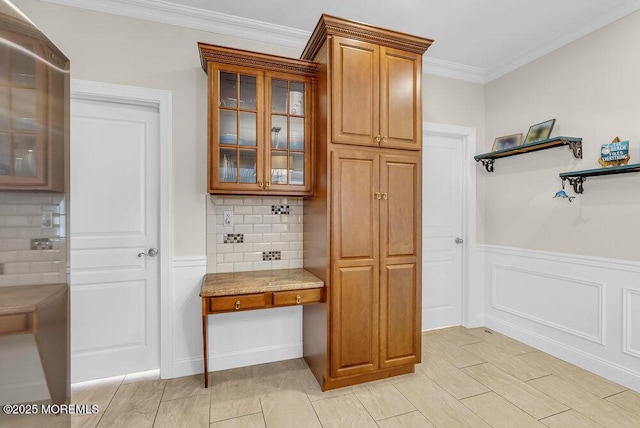 mudroom featuring ornamental molding and built in desk