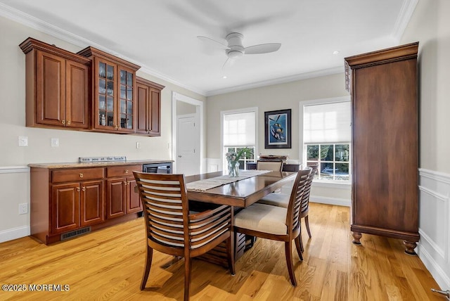 dining room featuring crown molding, ceiling fan, and light wood-type flooring