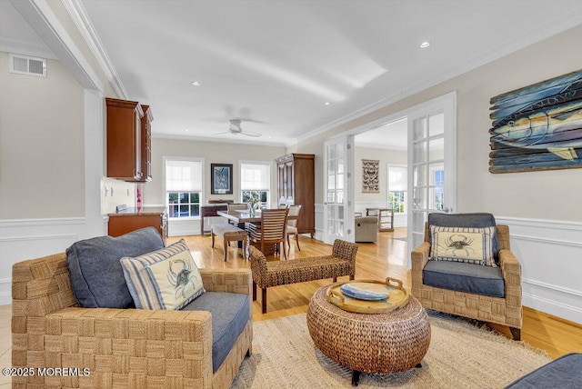 living room featuring french doors, ornamental molding, light hardwood / wood-style flooring, and a wealth of natural light