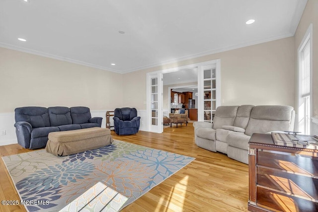 living room with french doors, crown molding, and light wood-type flooring