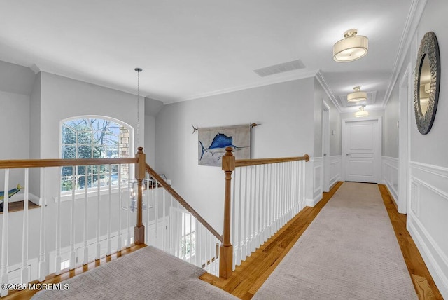 corridor with lofted ceiling, a notable chandelier, crown molding, and light hardwood / wood-style flooring