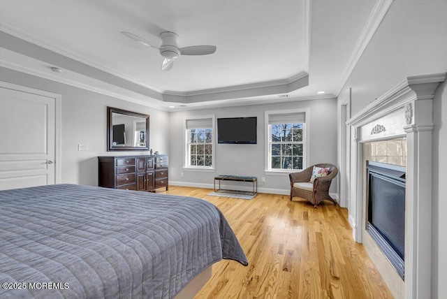 bedroom featuring crown molding, ceiling fan, a raised ceiling, and light wood-type flooring