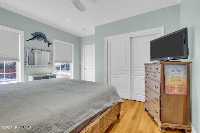 bedroom with crown molding, light hardwood / wood-style floors, a closet, and ceiling fan