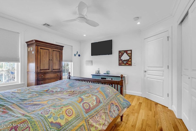 bedroom with crown molding, light hardwood / wood-style flooring, a closet, and ceiling fan