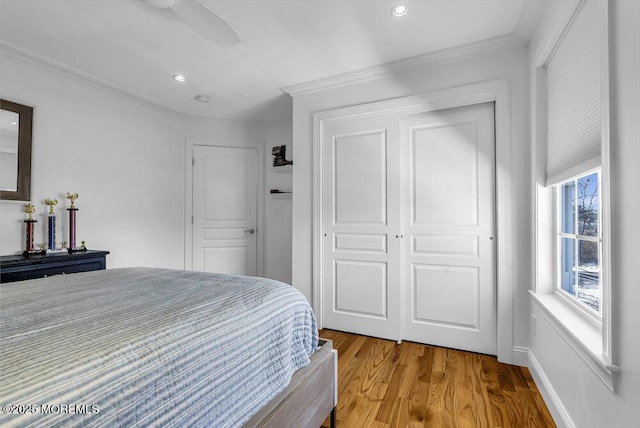 bedroom with hardwood / wood-style flooring, ceiling fan, crown molding, and a closet