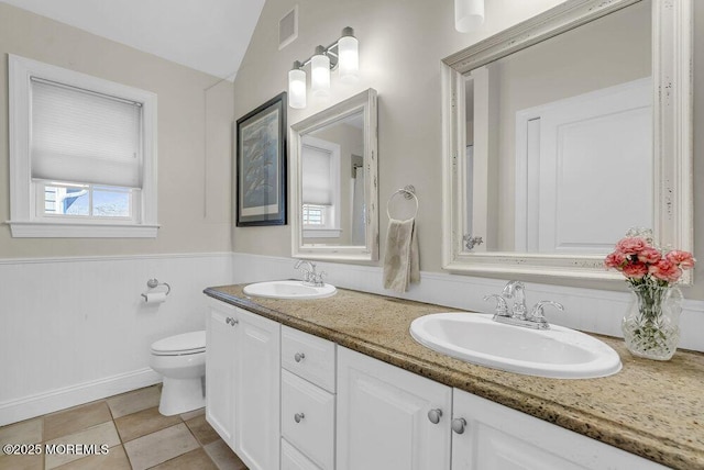 bathroom with lofted ceiling, toilet, tile patterned flooring, and vanity