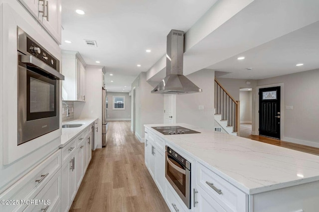 kitchen featuring sink, appliances with stainless steel finishes, light stone counters, white cabinetry, and extractor fan