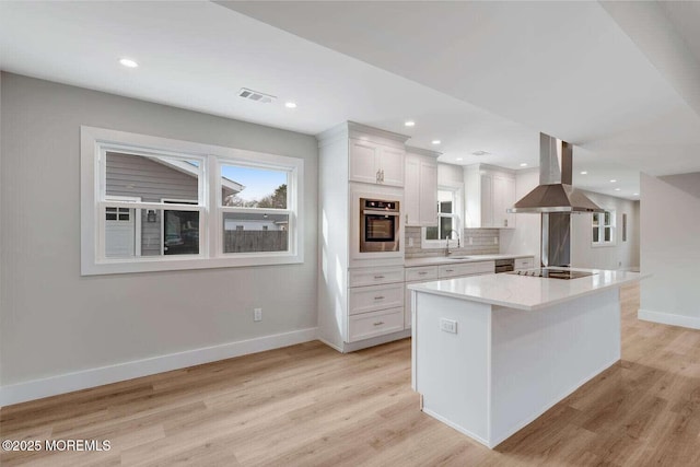 kitchen featuring a center island, stainless steel oven, backsplash, white cabinets, and island range hood