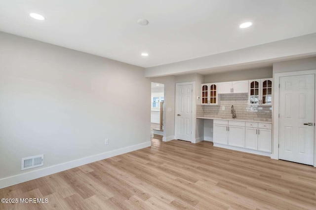 unfurnished living room with sink and light hardwood / wood-style floors