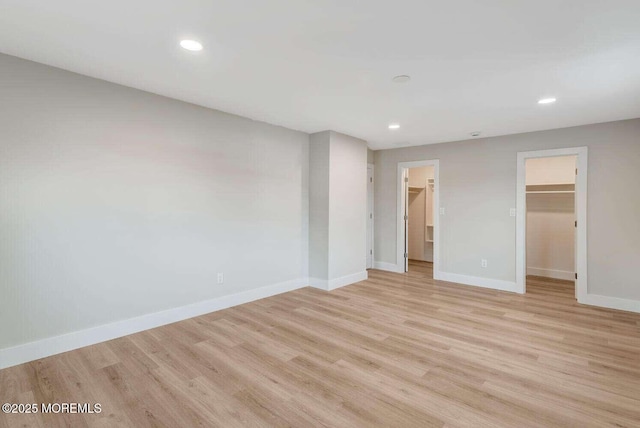 unfurnished bedroom featuring a spacious closet, light hardwood / wood-style flooring, and a closet