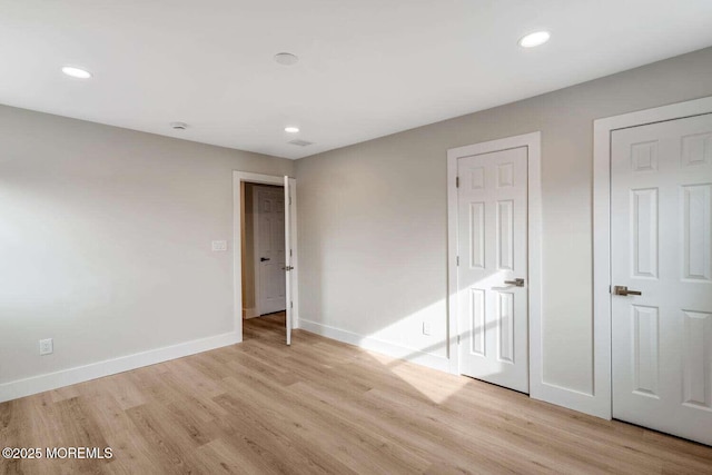 unfurnished bedroom with multiple closets and light wood-type flooring